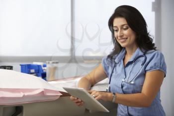 Female Doctor In Surgery Using Digital Tablet