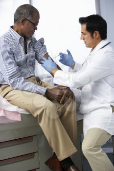 Doctor In Surgery Giving Male Patient Injection