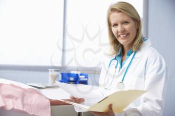 Female Doctor In Surgery Reading Patient Notes