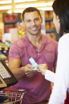 Customer Using Vouchers At Supermarket Checkout