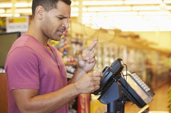 Hopeful Customer Paying For Shopping At Checkout With Card Crossing Fingers