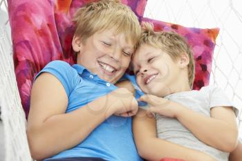 Two Young Boys Relaxing In Garden Hammock Together