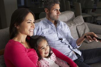 Hispanic Family Sitting On Sofa And Watching TV