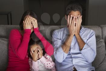 Frightened Hispanic Family Sitting On Sofa And Watching TV