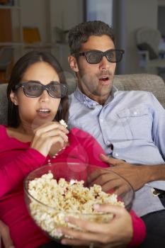 Couple On Sofa Watching TV Wearing 3D Glasses Eating Popcorn