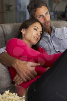 Hispanic Couple On Sofa Watching TV And Eating Popcorn
