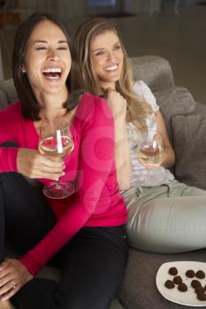 Two Women Sitting On Sofa Watching TV Drinking Wine