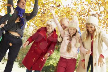 Multl Generation Family Throwing Leaves In Autumn Garden