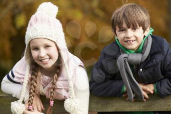 Portrait Of Two Children Leaning Over Wooden Fence