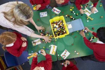 Overhead View Of Pupils And Teacher Working With Blocks
