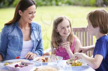 Mother And Children Enjoying Outdoor Meal Together