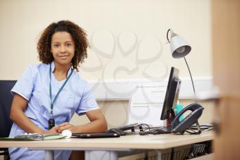 Portrait Of Female Nurse Working At Desk In Office