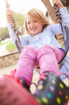 Young Girl Playing On Swing In Playground