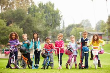 Young Children With Bikes And Scooters In Park
