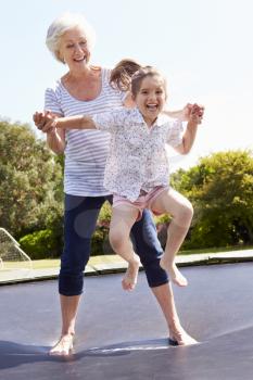Grandmother And Granddaughter Bouncing On Trampoline