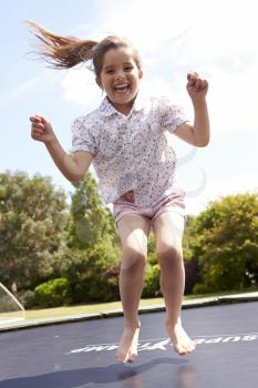 Portrait Of Girl Bouncing On Trampoline In Garden