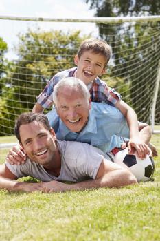 Grandfather, Grandson And Father With Football In Garden