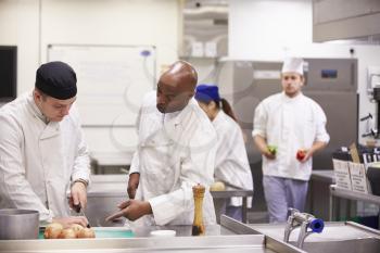Teacher Helping Students Training To Work In Catering