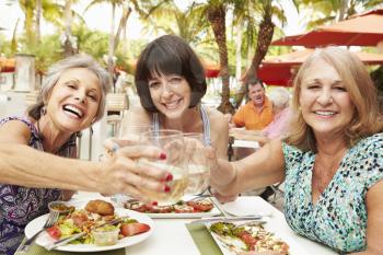 Senior Female Friends Eating Meal In Outdoor Restaurant