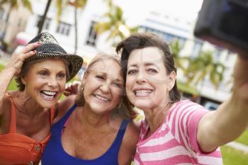 Three Senior Female Friends Taking Selfie In Park