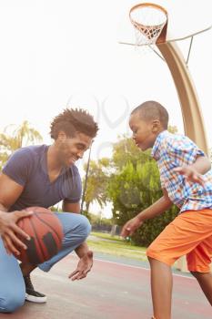 Father With Son Playing Basketball In Park Together