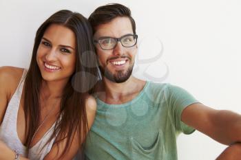 Portrait Of Couple Sitting Against White Wall