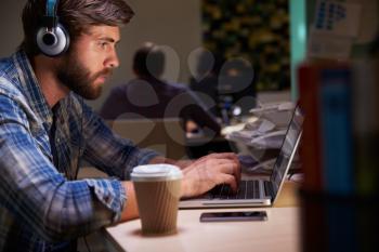 Office Worker With Coffee At Desk Working Late On Laptop