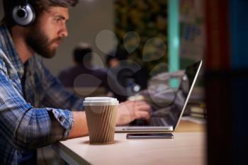 Office Worker With Coffee At Desk Working Late On Laptop