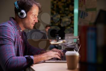 Male Office Worker With Coffee At Desk Working Late