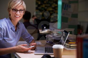 Female Office Worker With Coffee At Desk Working Late