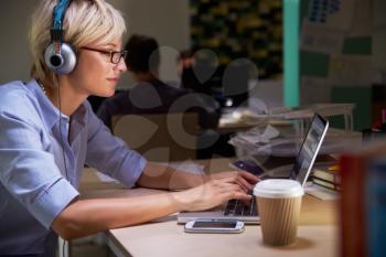 Female Office Worker With Coffee At Desk Working Late