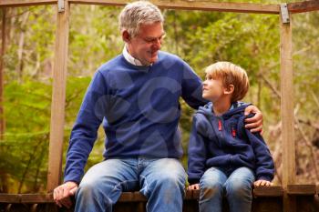 Grandfather with grandson on a bridge in a forest, close up