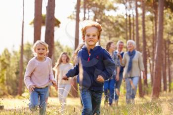 Multi-generation family walking in countryside, kids running