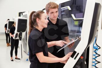 Two Young Engineers Operating CNC Machinery On Factory Floor