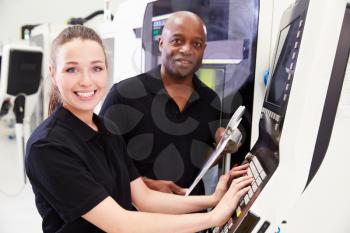 Portrait Of Apprentice Working With Engineer On CNC Machine