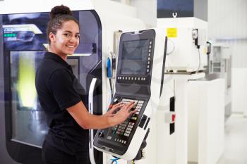 Female Engineer Operating CNC Machinery On Factory Floor