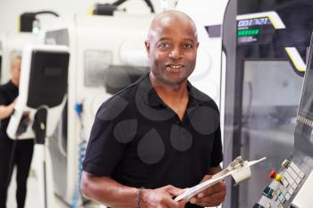 Portrait Of Male Engineer Operating CNC Machinery In Factory