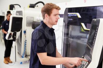 Male Engineer Operating CNC Machinery On Factory Floor
