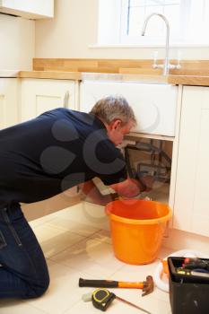 Middle aged male plumber fixing a kitchen sink