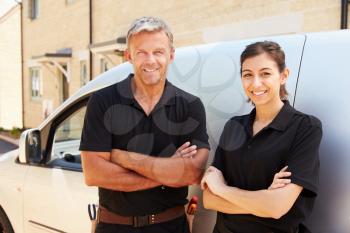 Portrait of male and female trade workers standing by a van