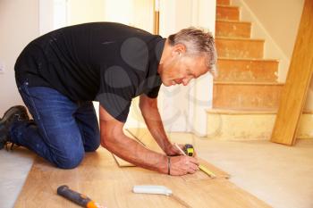 Man laying wood panel flooring during a house refurbishment