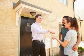 Real estate agent giving house keys to new property owners