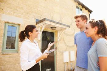 Young couple viewing a house with female real estate agent