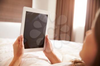 Woman Lying In Bed Whilst Using Digital Tablet