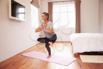 Woman Doing Yoga Fitness Exercises On Mat In Bedroom