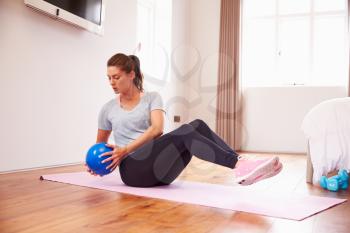 Woman With Ball Working Out To Fitness DVD On TV In Bedroom