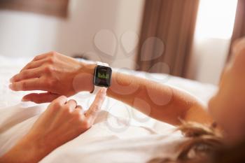 Woman Lying in Bed Whilst Checking Fitness App on Smart Watch