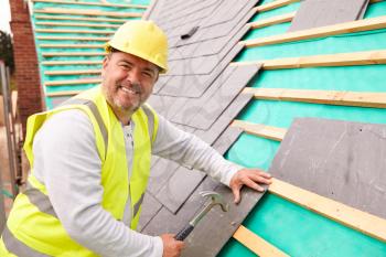 Construction Worker On Building Site Laying Slate Tiles
