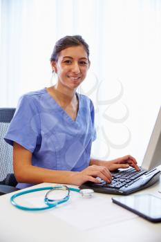 Portrait Of Female Doctor In Office Working At Computer