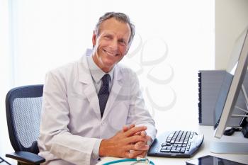 Portrait Of Male Doctor In Office Working At Computer